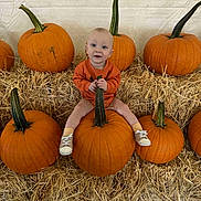 Dallas joined the competition — help win amazing prizes! baby, pumpkin, hay, orange_clothing, child, fall, autumn, smile, sitting, shoes, cute, harvest, festival, outdoor, seasonal, decor, person, head, background, celebration