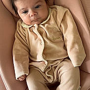 Zoé a rejoint le concours — aidez-le/la à gagner de superbes lots ! baby, infant, child, pajamas, soft_fabric, pink_cushion, seated, indoor, cute, face, portrait, clothing, newborn, relaxed, comfortable, small_hands, footed_pajamas, dark_hair, expression, home