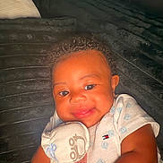 Jaylon is registered to the contest to win money with this photo: baby, bed, blanket, child, closeup, clothing, comfortable, cozy, cuddle, cute, face, furniture, happy, indoor, infant, person, portrait, smiling, soft_toy, warm