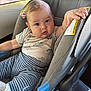 baby, car_seat, child, infant, dinosaur_print, striped_pants, clothing, seatbelt, car_interior, hand, face, eyes, cute, comfort, sitting, child_safety, transportation, person, young_child, curious