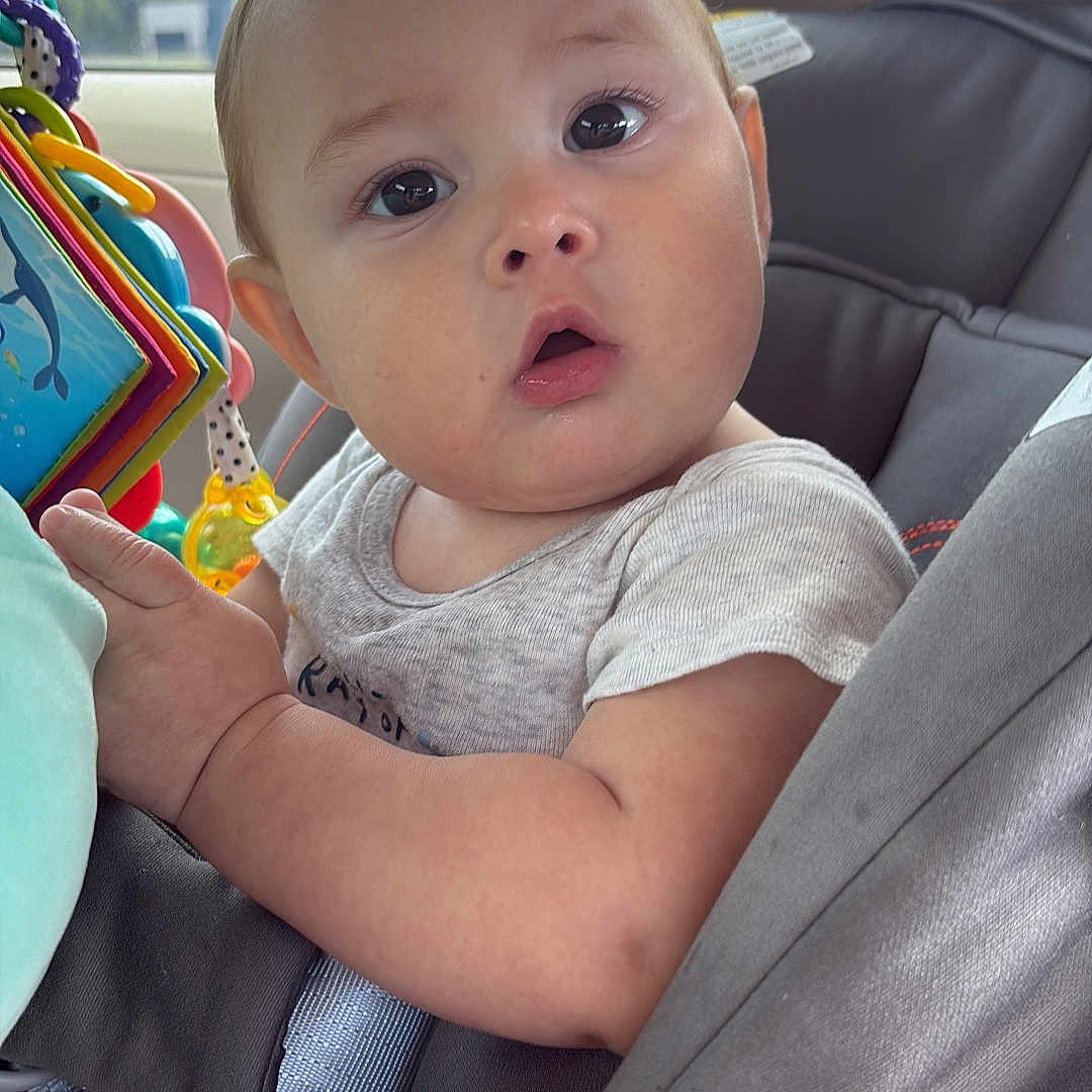 Austhin joined the competition — help win amazing prizes! baby, car_interior, car_seat, child, closeup, clothing, colorful, curious, cute, face, indoor, infant, open_mouth, person, portrait, seatbelt, soft_light, toy, wide_eyes, window