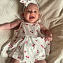 baby, baby_girl, blanket, cherry_pattern, child, clothing, cute, dress, fabric, happy, headband, headwear, indoors, infant, lying_down, person, playful, portrait, skin, smiling
