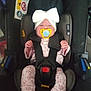 baby, car_seat, pacifier, headband, bow, pajamas, infant, child, seatbelt, safety, clothing, footwear, person, indoor, cute, sleepy, resting, child_safety, infant_care, transportation