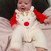 Lila joined the competition — help win amazing prizes! baby, child, onesie, reindeer, red_nose, tongue_out, happy, smiling, blanket, soft_toys, infant, cute, playful, indoors, warm_clothing, couch, legs, feet, head, face