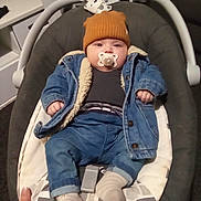 Lucas joined the competition — help win amazing prizes! baby, infant, pacifier, denim_jacket, hat, sock, baby_rocker, indoor, clothing, cute, child, person, cozy, face, headwear, sitting, furniture, hand, comfort, warm