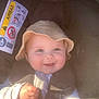 Lucas is registered to the contest to win money with this photo: baby, child, smile, hat, car_seat, seatbelt, warning_label, airbag, clothing, infant, cute, portrait, happy, baby_hand, young_child, indoor, seat, person, headwear, safety