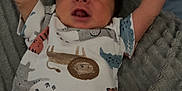 Hayden is registered to the contest to win money with this photo: baby, infant, onesie, animal_print, blanket, stretching, arms_up, sleepy, cozy, soft_texture, cute, newborn, person, child, indoors, resting, expression, face, head, clothing