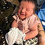 baby, newborn, smiling, pink_clothing, mittens, tattoo, arm, blanket, leopard_print, person, close_up, indoor, happy, cute, sleepy, infant, resting, cozy, skin, human