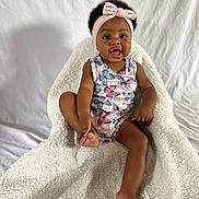 Cassidy is registered to the contest to win money with this photo: baby, blanket, clothing, couch, cushion, dress, face, furniture, happy, hat, head, homedecor, newborn, person, photography, portrait, quilt, sitting, smile, towel