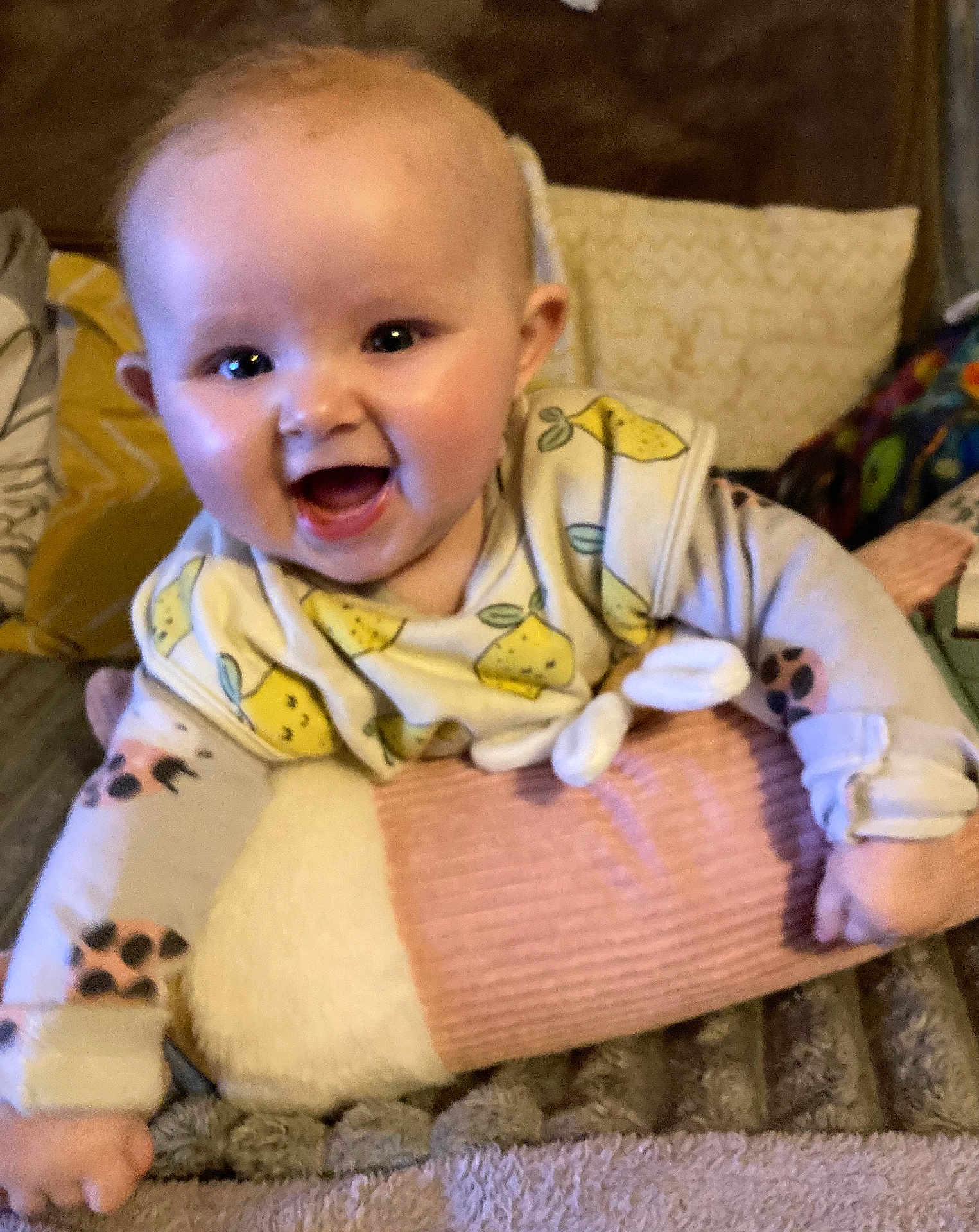 Daisy-Mae is registered to the contest to win money with this photo: baby, smiling, infant, cushion, blanket, pillow, lemon_pattern, clothing, happy, face, cute, indoors, child, soft_fabric, person, toddler, cozy, home, comfort, playful