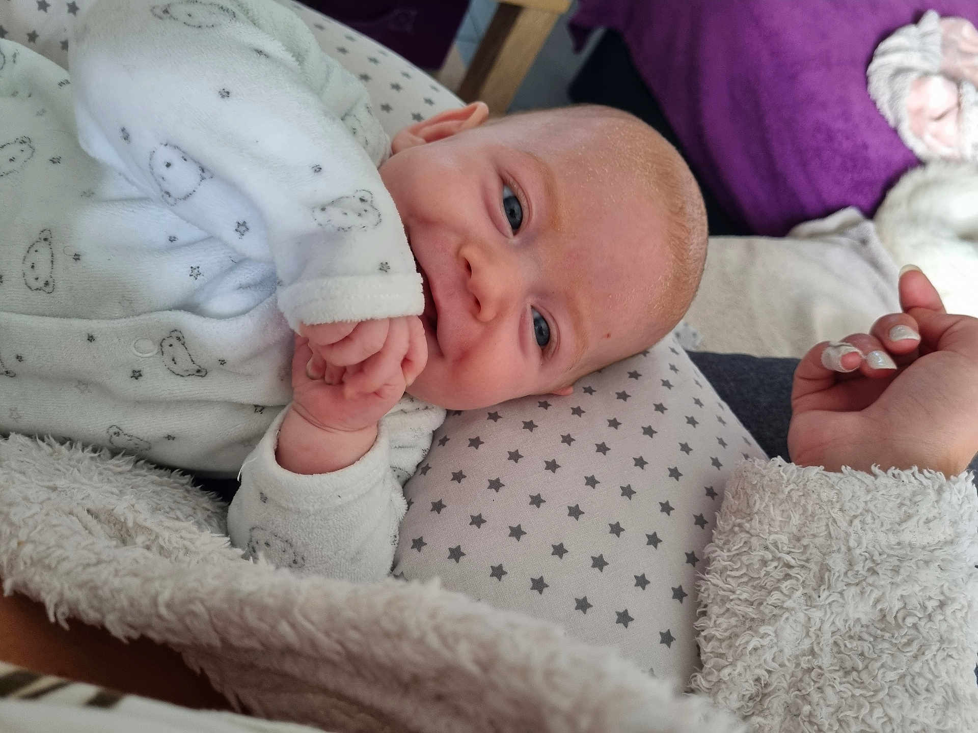 Wayan a rejoint le concours — aidez-le/la à gagner de superbes lots ! baby, infant, onesie, blanket, pillow, stars, hand, nails, fingers, blue_eyes, soft_texture, cute, sleepwear, cozy, indoor, person, face, smiling, lying_down, child