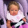 baby, child, infant, car_seat, lavender, pink_clothing, ruffled_shirt, curly_hair, portrait, sitting, harness, safety_buckle, vehicle_interior, indoors, face, eyes, hands, fashion, adorable, photograph