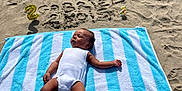Gabriel a rejoint le concours — aidez-le/la à gagner de superbes lots ! baby, towel, beach, sand, balloon, number, name, birthday, striped_towel, infant, sunlight, relaxing, outdoor, summer, child, person, celebration, blue, white, casual