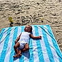 baby, towel, beach, sand, balloon, number, name, birthday, striped_towel, infant, sunlight, relaxing, outdoor, summer, child, person, celebration, blue, white, casual
