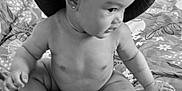 Noëlya a rejoint le concours — aidez-le/la à gagner de superbes lots ! baby, bed, bedspread, black_and_white, child, curious, cute, earring, expression, floral_pattern, foot, hand, hat, indoors, infant, monochrome, person, portrait, sitting, skin