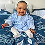 Noëlya a rejoint le concours — aidez-le/la à gagner de superbes lots ! baby, bedroom, bedspread, blue, child, cute, fabric, face, furniture, happy, head, home, indoors, infant, pattern, person, sitting, smiling, striped_clothing, tights