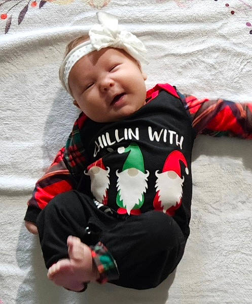 Lyla is registered to the contest to win money with this photo: baby, baby_products, baby_toddler_clothing, carmine, child, comfort, face, fictional_character, grass, happy, head, headwear, linens, pattern, person, sitting, sleeve, smile, toddler, winter