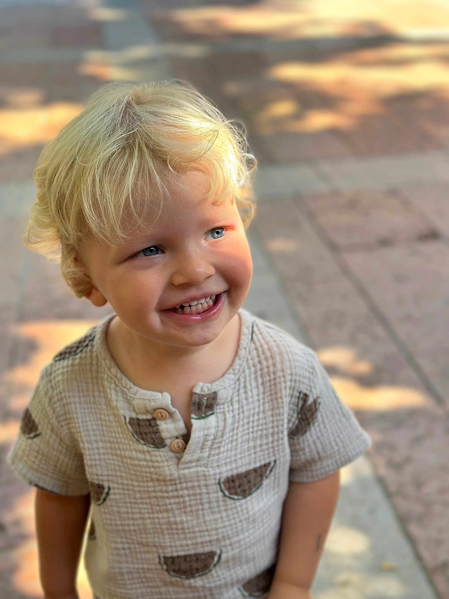 Noa a rejoint le concours — aidez-le/la à gagner de superbes lots ! toddler, child, blond_hair, smiling, blue_eyes, shirt, watermelon_pattern, outdoor, sunlight, shadow, curly_hair, happy, portrait, person, cute, young_child, daylight, face, standing, casual_clothing