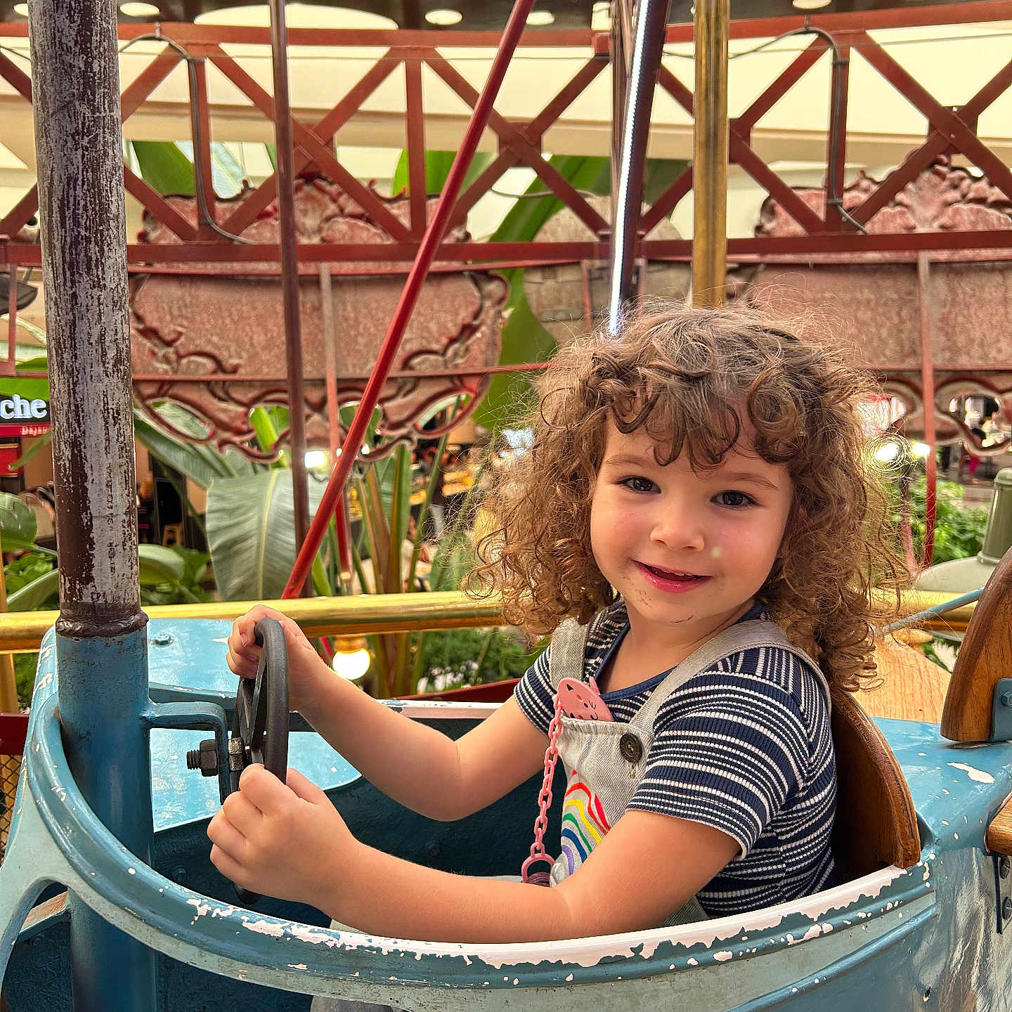 Djodie a rejoint le concours — aidez-le/la à gagner de superbes lots ! amusement_ride, blue_car, carnival, child, curly_hair, daylight, greenery, happy, metal, outdoor, overalls, person, plants, playful, rust, seat, smile, steering_wheel, striped_shirt, vintage