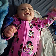 Nova joined the competition — help win amazing prizes! baby, infant, smiling, pink_clothing, minnie_mouse, onesie, blanket, bed, happy, cute, face, person, child, sleepwear, soft, lying_down, cozy, indoor, expression, cheerful