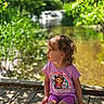 Brylee joined the competition — help win amazing prizes! child, toddler, curly_hair, purple_clothing, sitting, wooden_deck, pond, water, greenery, outdoor, sunlight, shadows, nature, summer, daylight, cartoon_tshirt, casual, portrait, side_view, peaceful