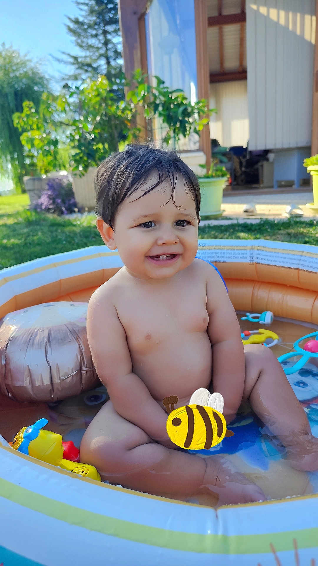 Sacha is registered to the contest to win money with this photo: toddler, child, pool, water, summer, outdoor, inflatable_pool, toy, smiling, happy, grass, garden, sunlight, house, playing, wet_hair, sitting, cute, baby, fun
