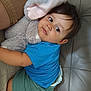baby, blue_shirt, child, comfort, couch, cute, face, foot, green_shorts, hair, indoor, leather_couch, person, plush, relaxing, skin, soft_toy, stuffed_animal, toddler, toy