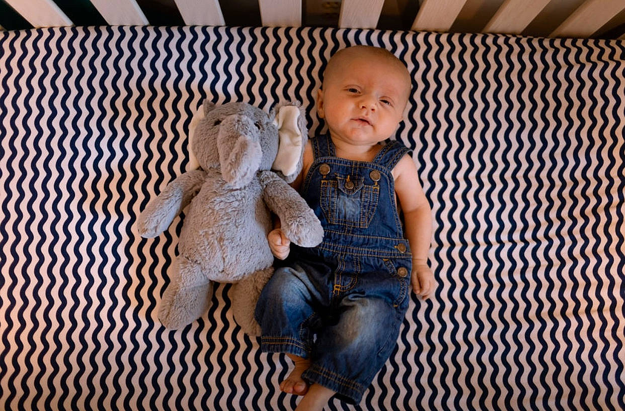 Greysen is registered to the contest to win money with this photo: baby_toddler_clothing, cheek, clothing, comfort, denim, doll, fawn, flooring, foot, happy, head, pattern, person, sitting, skin, sleeve, smile, textile, toddler, toy