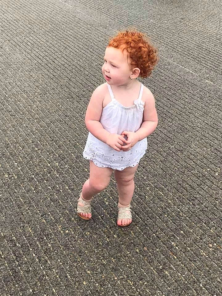 Harleigh is registered to the contest to win money with this photo: asphalt, baby, baby_toddler_clothing, barefoot, blond, child, flooring, foot, fun, gesture, grass, human_leg, knee, people_in_nature, person, road_surface, sitting, sleeve, t_shirt, toddler