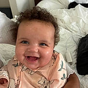 Halo joined the competition — help win amazing prizes! baby, smile, curly_hair, infant, clothing, person, hand, bed, blanket, indoor, cute, happy, child, portrait, cozy, fabric, human_face, sleeve, animal_print, skin