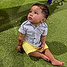 baby, child, toddler, sitting, outdoor, playground, grass, portrait, face, smiling, curious, looking_up, striped_shirt, yellow_shorts, barefoot, play_area, nighttime, artificial_grass, playground_equipment, photography