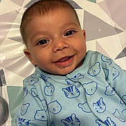 Anthony is registered to the contest to win money with this photo: baby, smile, face, infant, blue_onesie, bear_pattern, tiger_pattern, clothing, lying_down, geometric_pattern, mat, cute, happy, child, portrait, indoors, skin, head, eyes, mouth