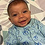 baby, smile, face, infant, blue_onesie, bear_pattern, tiger_pattern, clothing, lying_down, geometric_pattern, mat, cute, happy, child, portrait, indoors, skin, head, eyes, mouth