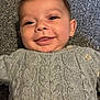apparel, baby, button, child, closeup, cozy, cute, face, gray, happy, indoor, infant, knitwear, lying_down, person, portrait, smiling, sweater, texture, warm