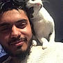 beard, black_and_white_cat, casual, cat, close_up, companion, curious, dark_background, feline, friendship, human, indoor, man, pet, portrait, selfie, shoulder, smile, texture, white_sweater