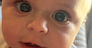 Marley joined the competition — help win amazing prizes! baby, child, infant, portrait, face, eyes, wide_eyed, curious, drool, bib, colorful_clothing, yellow, indoor, close_up, sunlight, warm_lighting, head, smiling, camera, photograph