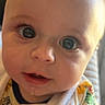 baby, child, infant, portrait, face, eyes, wide_eyed, curious, drool, bib, colorful_clothing, yellow, indoor, close_up, sunlight, warm_lighting, head, smiling, camera, photograph