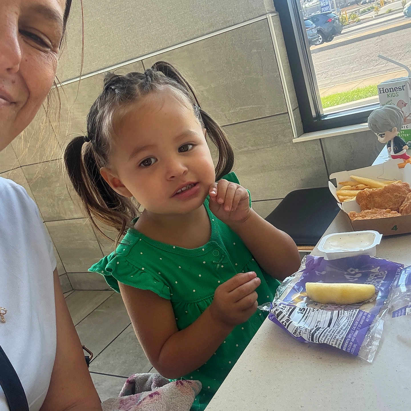Kayleah is registered to the contest to win money with this photo: casual, chicken_nuggets, child, curious, dipping_sauce, face, figurine, food, fries, girl, green_dress, indoor, parking_lot, person, pigtails, restaurant, snack_pack, table, window, woman