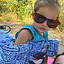 Kayleah is registered to the contest to win money with this photo: child, sunglasses, floatation_device, orca, outdoor, nature, greenery, summer, sunlight, casual, hair, face, person, water_safety, playful, family, fun, daytime, blue, clothing