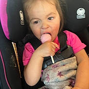 Kayleah joined the competition — help win amazing prizes! toddler, child, car_seat, lollipop, blanket, pink_shirt, seatbelt, indoors, person, cute, young_child, eating, food, hand, head, hair, face, comfort, seat, casual