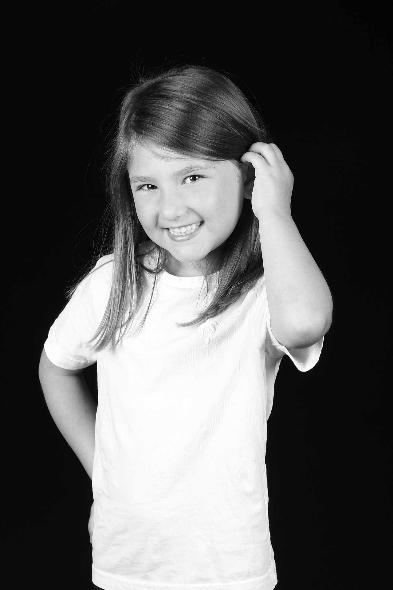Elyna participe au concours pour gagner de l'argent avec cette photo : child, girl, smile, white_shirt, long_hair, black_background, portrait, happy, posing, young, cute, casual, standing, female, monochrome, studio, confident, hand_on_hip, playful, youth