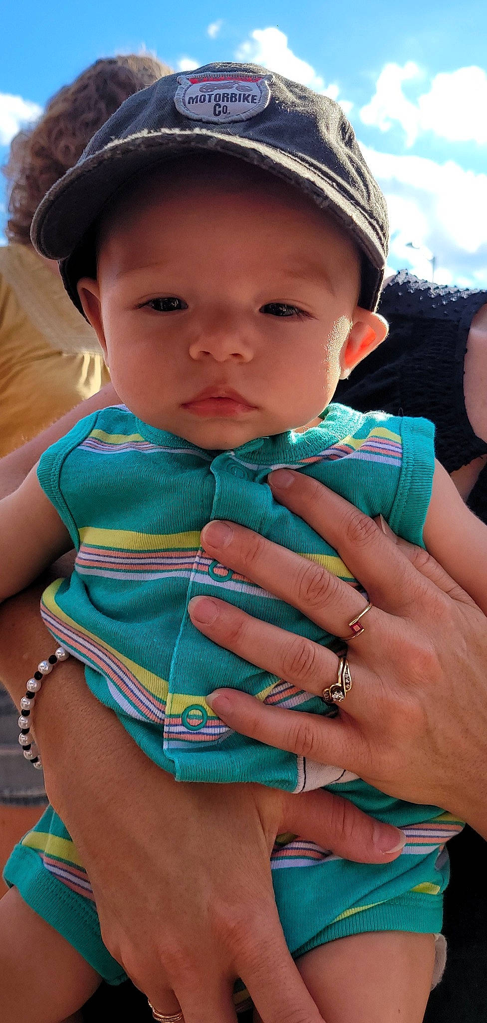 Hudson is registered to the contest to win money with this photo: aqua, azure, baby, baby_toddler_clothing, blue, cap, face, finger, gesture, grass, green, happy, headwear, lip, mouth, nail, people, person, photograph, skin