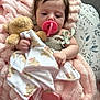 baby, pacifier, blanket, teddy_bear, pink, soft_texture, infant, cute, sleepy, cushion, floral, child, holding, resting, indoors, comfort, toddler, hand, face, portrait