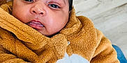Radjeshwaren a rejoint le concours — aidez-le/la à gagner de superbes lots ! baby, infant, child, face, hand, fingers, clothing, jacket, brown, curly_hair, skin, indoor, floor, blanket, cute, portrait, expression, pointing, person, cozy