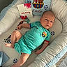 Emilio a rejoint le concours — aidez-le/la à gagner de superbes lots ! baby, infant, onesie, blue, white, pillow, card, toy, cradle, soccer, sports, celebration, milestone, person, child, cute, sleeping_area, clothing, face, lying_down