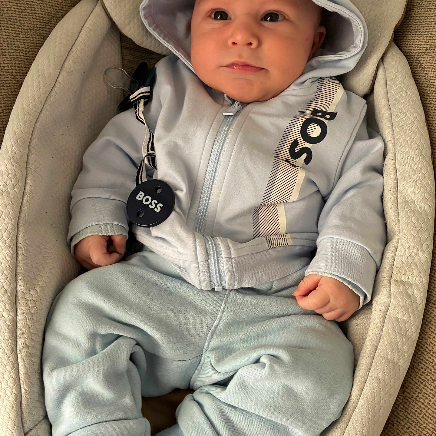 Emilio participe au concours pour gagner de l'argent avec cette photo : baby, infant, child, hoodie, blue_clothing, socks, baby_seat, cushion, cute, portrait, indoors, relaxed, small_hands, comfortable, casual_wear, expression, face, looking, seated, soft_fabric