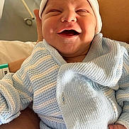 Emilio participe au concours pour gagner de l'argent avec cette photo : baby, newborn, smiling, knitted_clothing, blue, white, hat, infant, happy, portrait, indoor, person, hand, cozy, wrapped, cute, warm, sitting, face, human