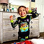 Mckenzie is registered to the contest to win money with this photo: child, smiling, pajamas, indoor, bedroom, dresser, mirror, lamp, photo_album, bed, happy, person, furniture, toy, colorful, playful, home, carpet, illustration, clothing