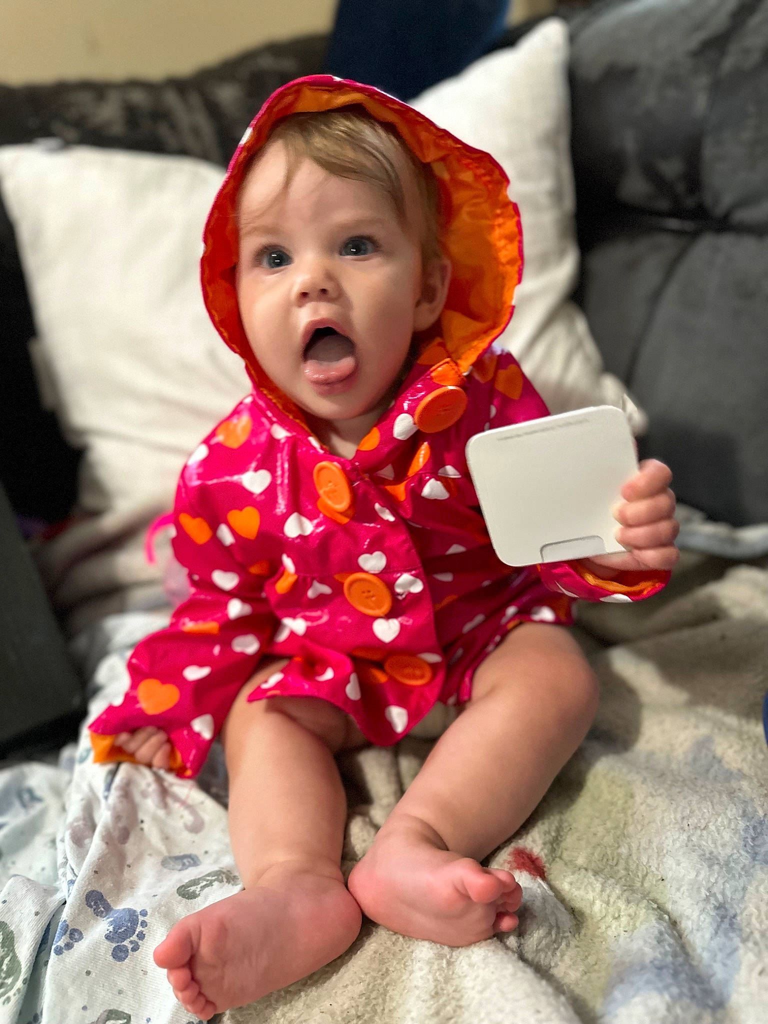 Faye is registered to the contest to win money with this photo: baby_toddler_clothing, cheek, child, comfort, face, facial_expression, fun, happy, human, human_body, human_leg, lap, linens, magenta, person, pink, sitting, skin, sleeve, surprise