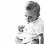 toddler, child, boy, portrait, black_and_white, toy, lion_toy, shirt, pants, barefoot, sitting, curious, expression, closeup, indoor, soft_light, casual_clothing, cute, young_child, face